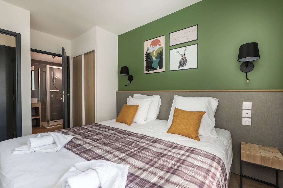 A hotel room with a bed, a green wall, and a shower area.