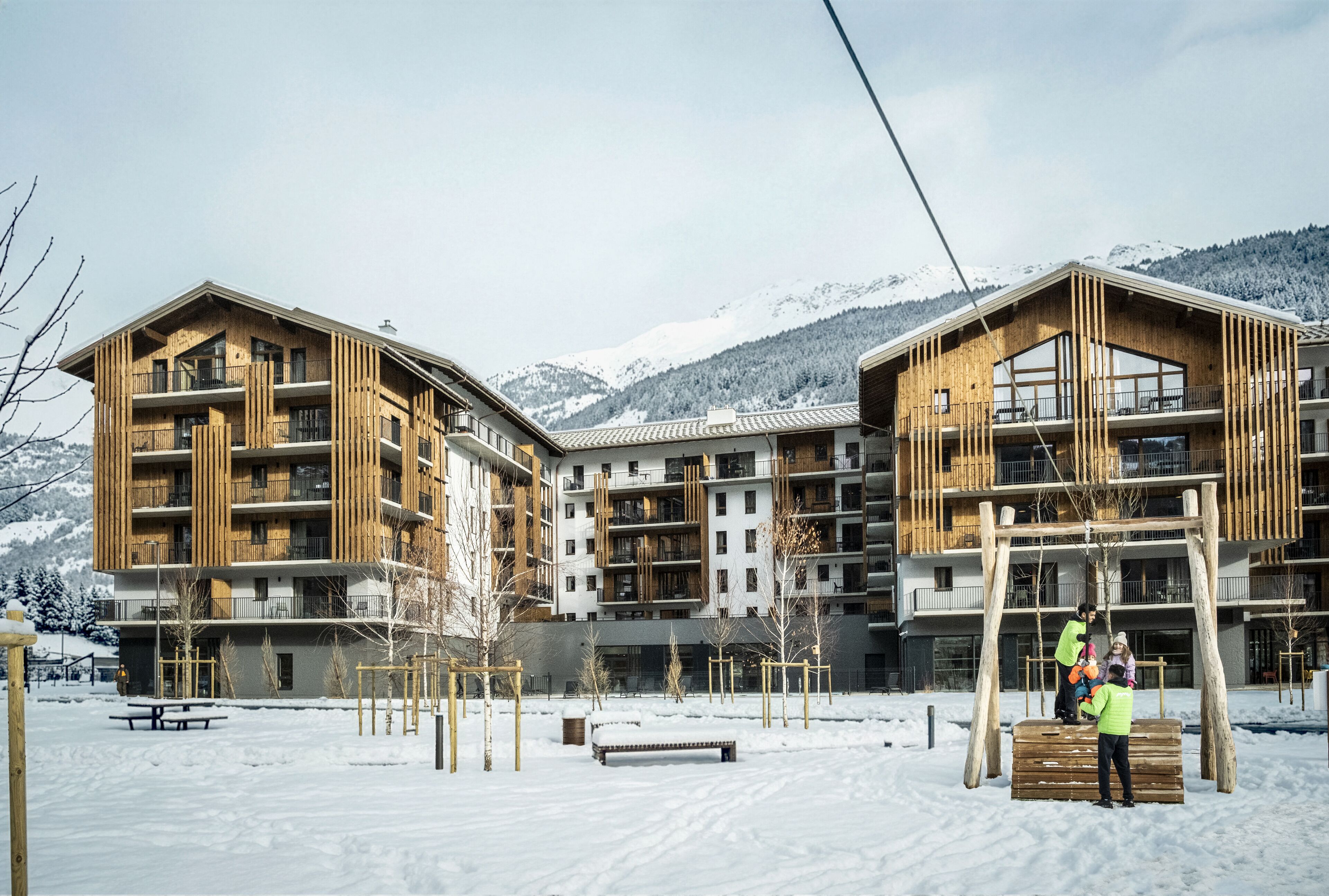 A modern building with multiple balconies and a snowy landscape in the background.