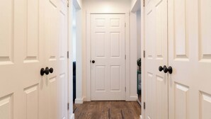 Un pasillo con puertas blancas y suelo de madera.