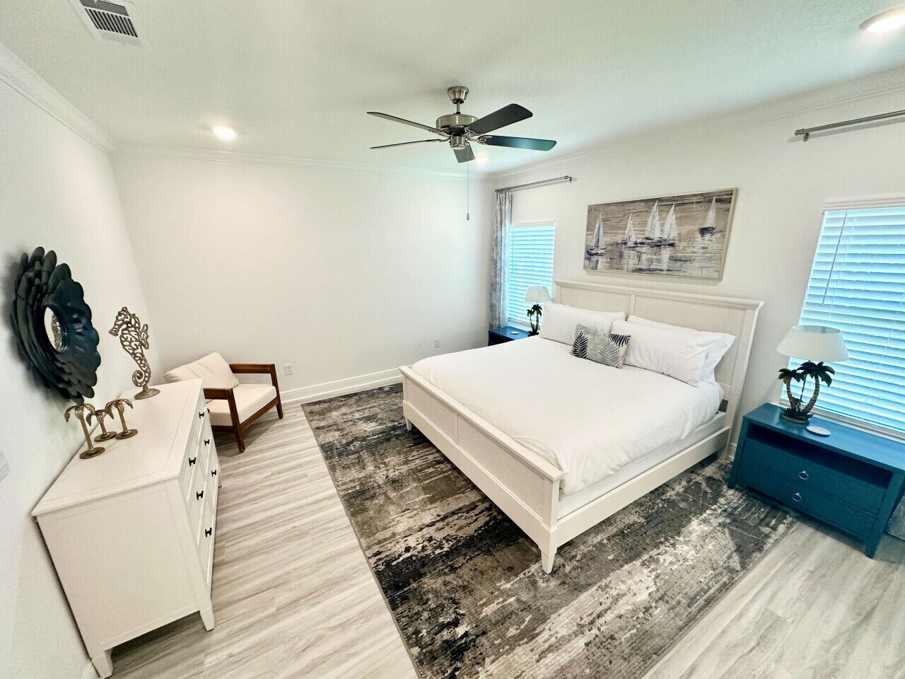 A bedroom with a bed, dresser, nightstand, and ceiling fan.
