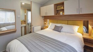 Un dormitorio con una cama grande, una mesita de noche, un espejo y un armario.