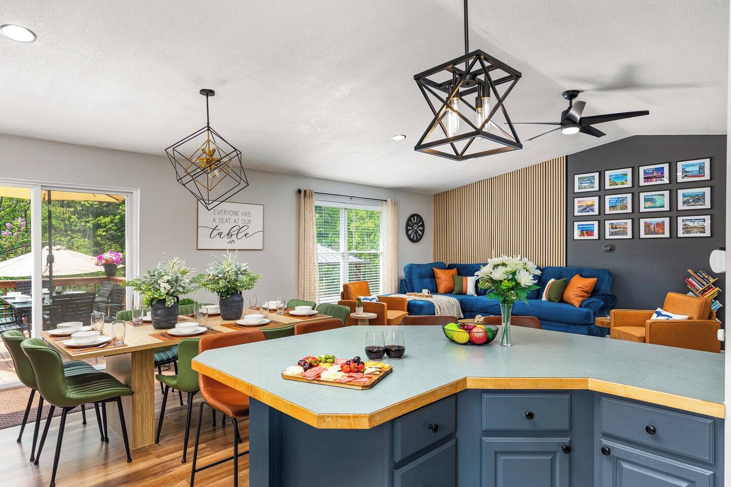 A modern kitchen with a central island, dining area, and a living space with a blue sofa and decorative pillows.