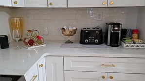 Una cocina con armarios blancos, una cafetera, un tostador y un cuenco de fruta.