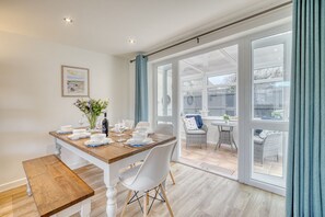 A dining area with a wooden table set for four, white chairs, and a bench.