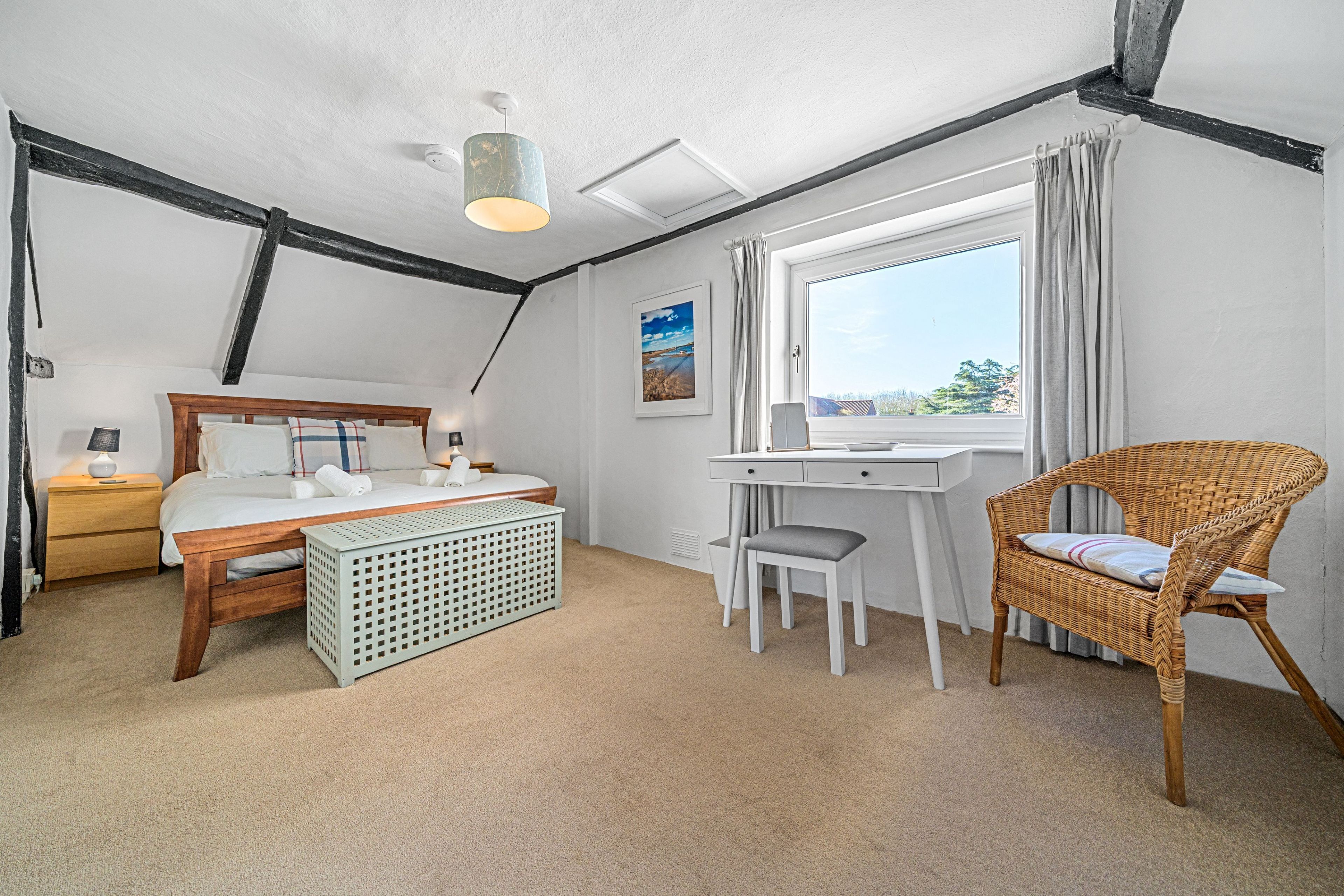 A bedroom with a bed, desk, chair, and a view of the outdoors.