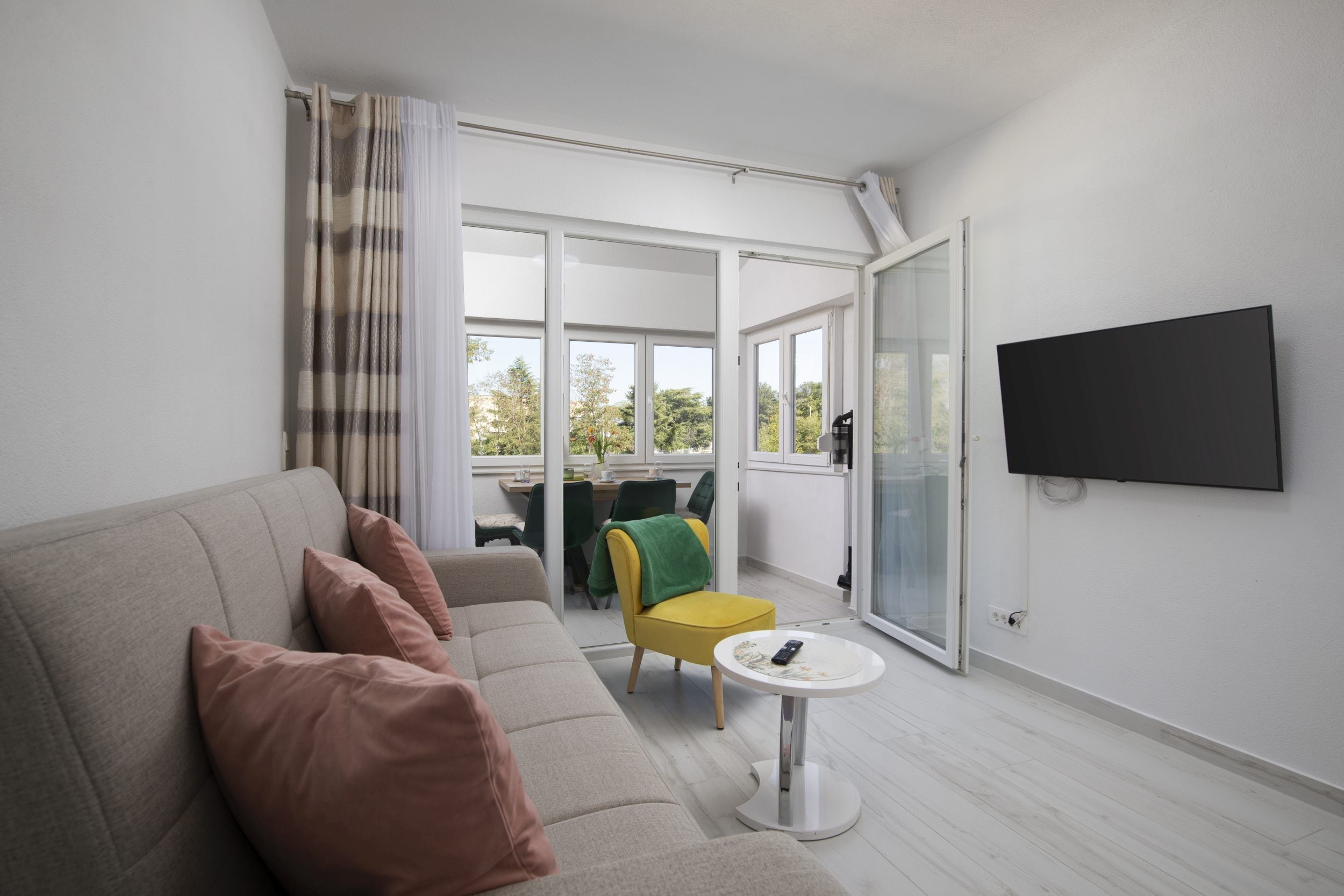 Una sala de estar moderna con un sofá, una mesita redonda y un televisor montado en la pared.