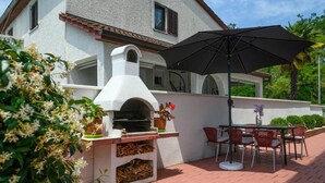 An outdoor patio with a brick floor, a white oven, and a table with chairs.