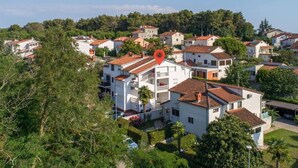 A residential area with white buildings, red-tiled roofs, and lush greenery.