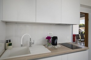 A modern kitchen with a white sink, stainless steel faucet, and a wooden countertop.