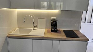A modern kitchen with a built-in sink, a coffee maker, and a wooden countertop.