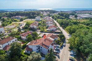 An aerial view of a residential area with houses, a road, and a body of water in the background. - Apartment SoMi 1 (Porec)