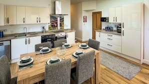 A modern kitchen with white cabinets, a dining table set for four, and a skylight above.