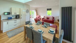 A modern kitchen with a dining area, a red sofa, and a view of the outdoors.