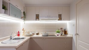 Une cuisine moderne avec des armoires blanches, un évier en acier inoxydable et un four à micro-ondes encastré.