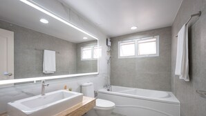 Une salle de bain moderne avec deux lavabos, des toilettes, une baignoire et un grand miroir.