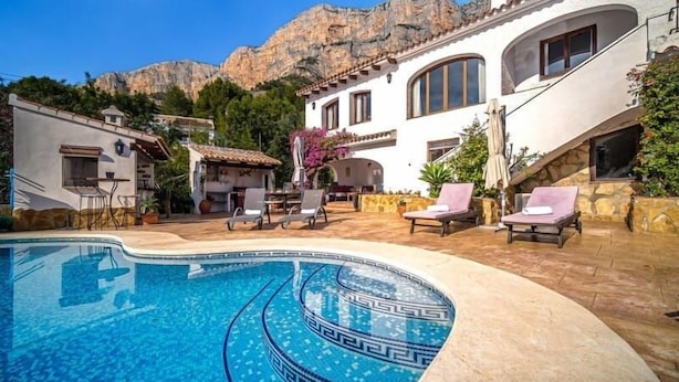 A pool area with lounge chairs, a dining area, and a mountain backdrop. - Casa Andrea 4 bed, 4 bath Villa with pool in Javea (Xàbia)