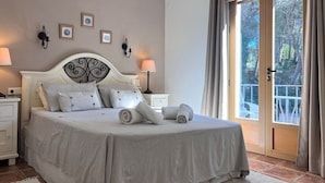A neatly made bed with a headboard, bedside tables with lamps, and a view of the outdoors through a glass door. - Casa Andrea 4 bed, 4 bath Villa with pool in Javea (Xàbia)