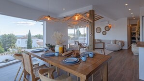 A modern dining area with a wooden table set for a meal, surrounded by wicker chairs.