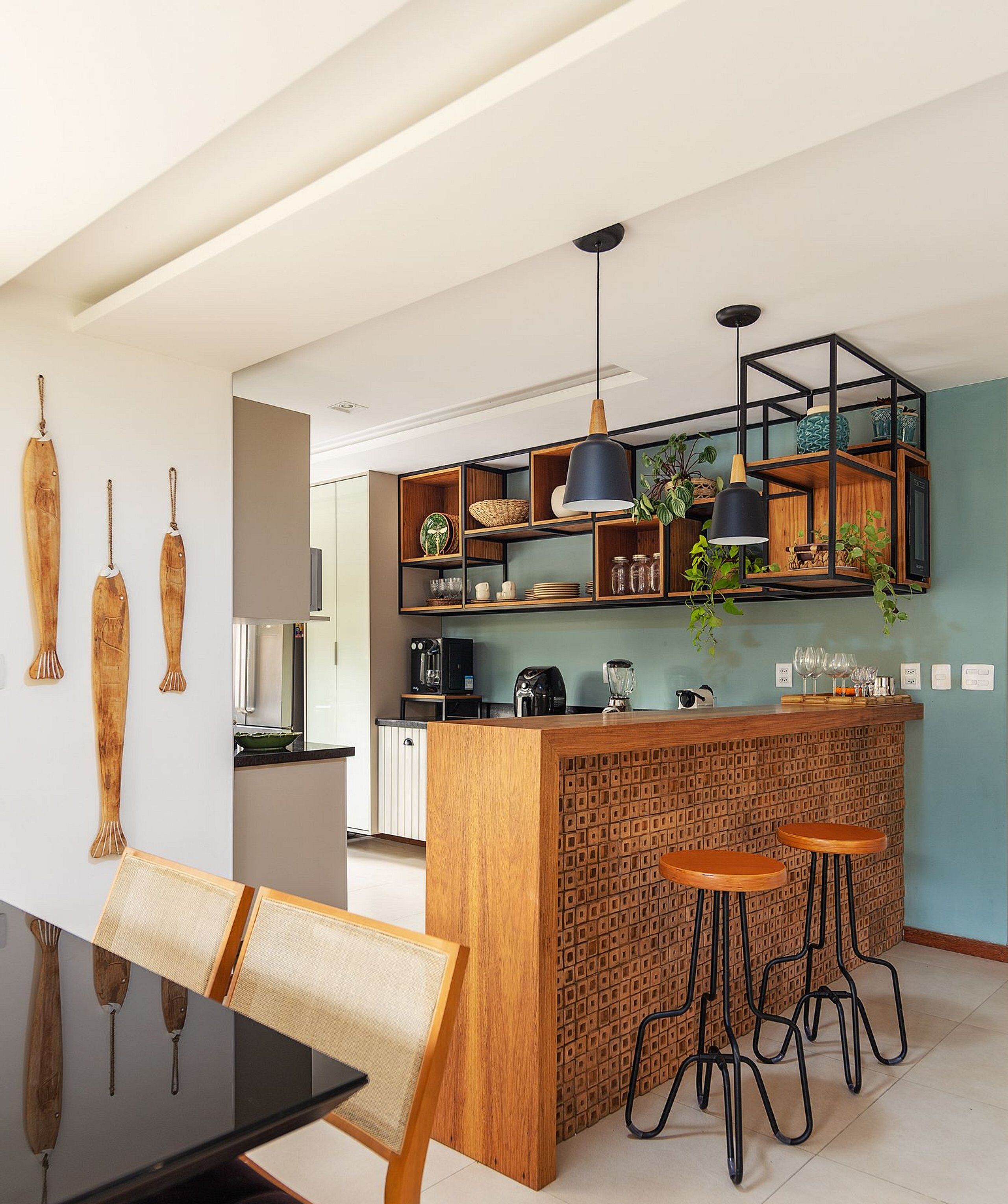 A modern kitchen with a wooden island, bar stools, and pendant lighting.