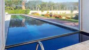 A swimming pool with a clear view of a landscaped garden and trees in the background. - Bz15 Casa 200 metros da praia 4 suítes (Buzios)