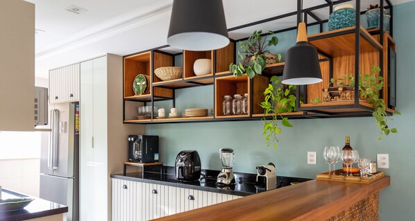 Una cocina moderna con estantes de madera, una encimera negra y diversos electrodomésticos.