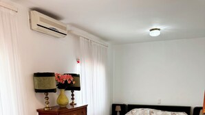 Une chambre d’hôtel équipée d’un lit, d’une chaise, d’une table de chevet, d’une lampe et d’un appareil de climatisation.