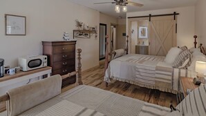 A cozy bedroom with two beds, a wooden dresser, a microwave, and a ceiling fan. - The Inn at Beulah Farm - The Pen (Whitley City)