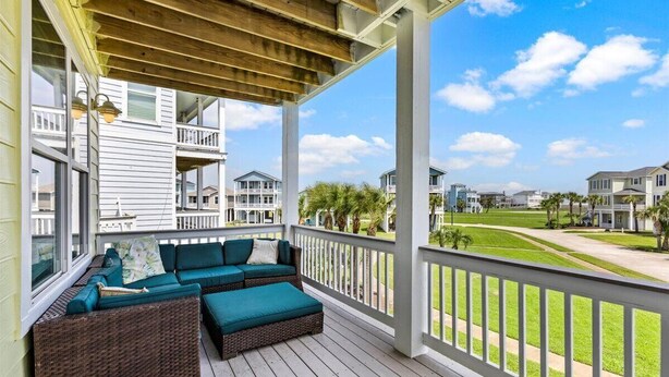A covered porch with wicker furniture and a view of a residential area. - 4/4 - Direct Boardwalk to Beach - Neighborhood Beach Club - Beach Views (Galveston)