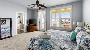 A bedroom with a bed, a ceiling fan, a TV, a dresser, and a window with blinds. - 4/4 - Direct Boardwalk to Beach - Neighborhood Beach Club - Beach Views (Galveston)