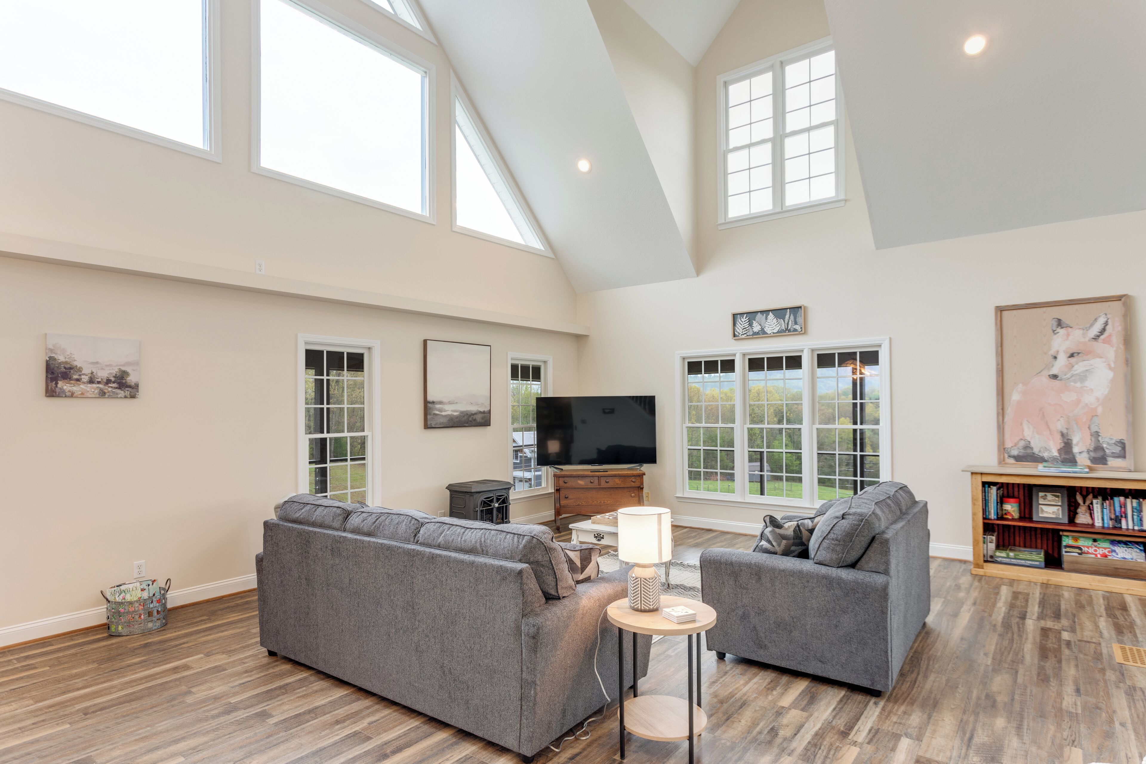 A spacious living room with two grey sofas, a TV, and a bookshelf.