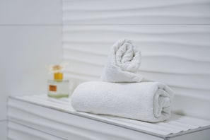 A neatly folded white towel on a white dresser with a bottle of lotion. - Modern apartment Marijan  (Makarska)