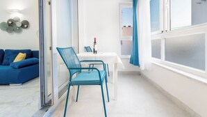 A modern living room with a blue sofa, a dining table with chairs, and a large window with curtains. - Modern apartment Marijan  (Makarska)