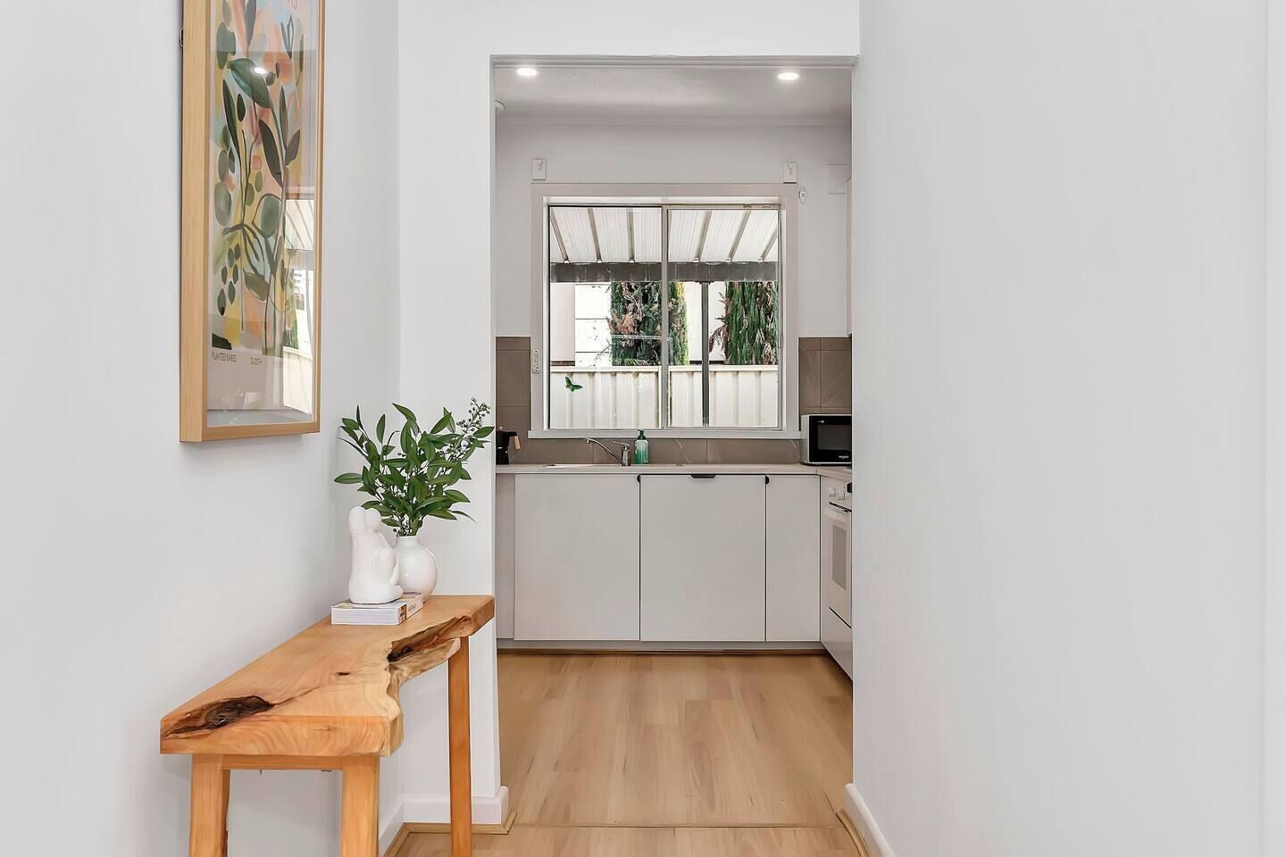 Timber details and curated artwork create a warm welcome in the hallway, which leads directly to the kitchen.