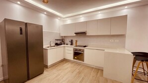Eine moderne Küche mit weißen Schränken, einem Edelstahlkühlschrank und einem eingebauten Ofen.
