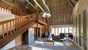A spacious kitchen with a granite countertop, wooden staircase, and a dining area with a sofa and table. - Lichenry Bush Lodge (Mogalakwena)