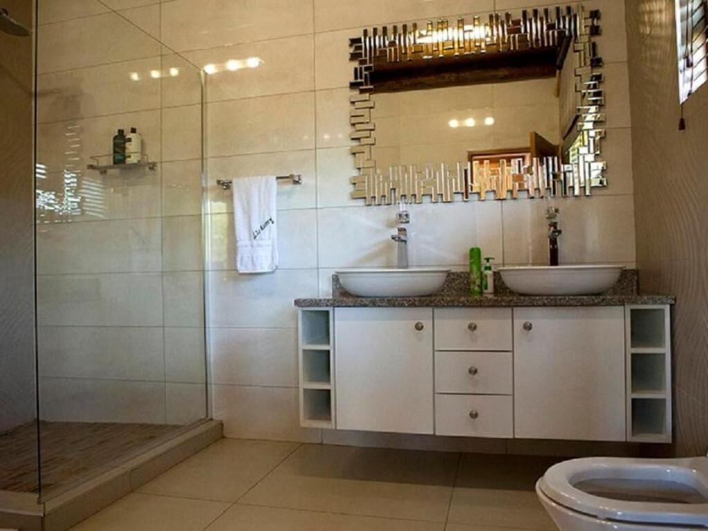 A modern bathroom with a glass shower enclosure, a white sink vanity with a mirror, and a toilet.