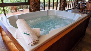 A hot tub with a towel labeled "Licherry" and a wooden deck with outdoor furniture. - Lichenry Bush Lodge (Mogalakwena)