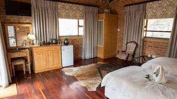 Una habitación con un escritorio de madera, una cama, una silla y un refrigerador pequeño.