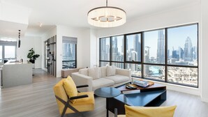 A modern living room with a sofa, armchairs, and a coffee table, large windows with a city view, and a kitchen area. - South Ridge - Mint Stay (Dubai)
