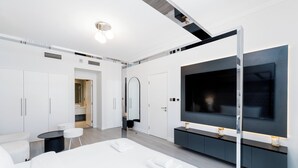 A modern hotel room with a large bed, a TV mounted on the wall, a small seating area, and a walk-in closet. - South Ridge - Mint Stay (Dubai)