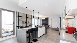 A modern kitchen with a central island, bar stools, and a red appliance. - South Ridge - Mint Stay (Dubai)