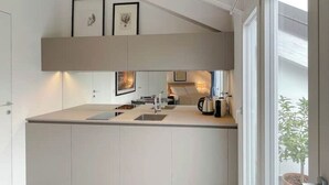 Een moderne keuken met een centraal eiland, witte keukenkastjes en een groot raam dat voor natuurlijk licht zorgt.