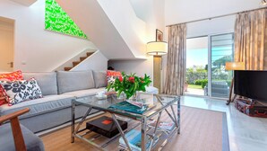 A modern living room with a glass coffee table, grey sofa, and a staircase leading to an upper level. - Genteel Home Casa Aloha Golf (Marbella)