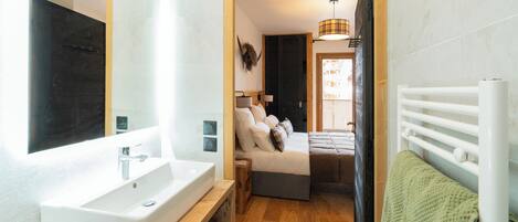 Un baño moderno con un espejo grande, lavamanos blanco y tocador de madera.