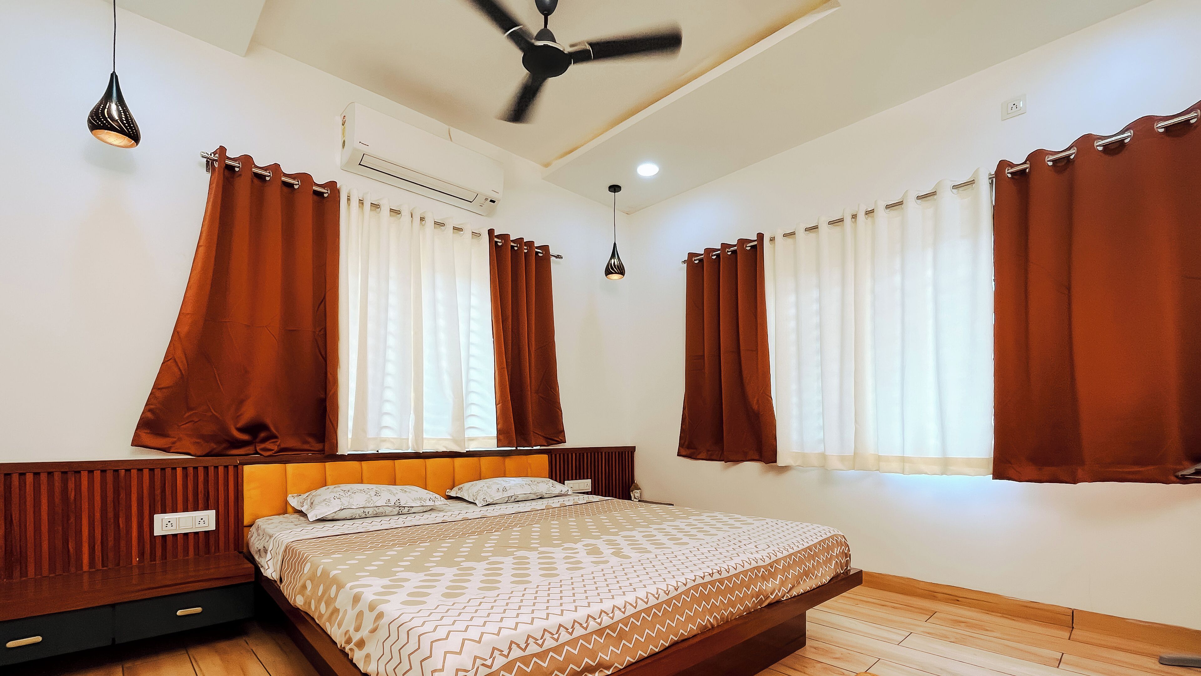 A bedroom with a bed, curtains, a ceiling fan, and an air conditioning unit.
