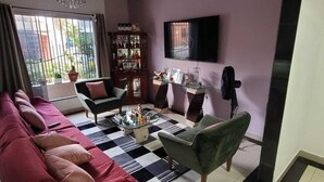 Un saló amb un sofà, cadires, una taula de centre, un televisor i una prestatgeria.