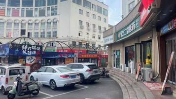 A street with parked cars and a building with multiple storefronts.