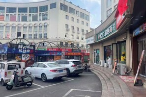 Una calle con coches estacionados y un edificio con varias tiendas.