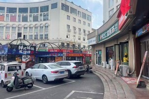 Una calle con coches estacionados y un edificio con varias tiendas.