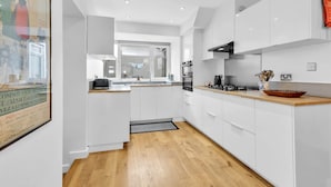 Une cuisine moderne avec des meubles blancs, un plan de travail en bois et une hotte noire.